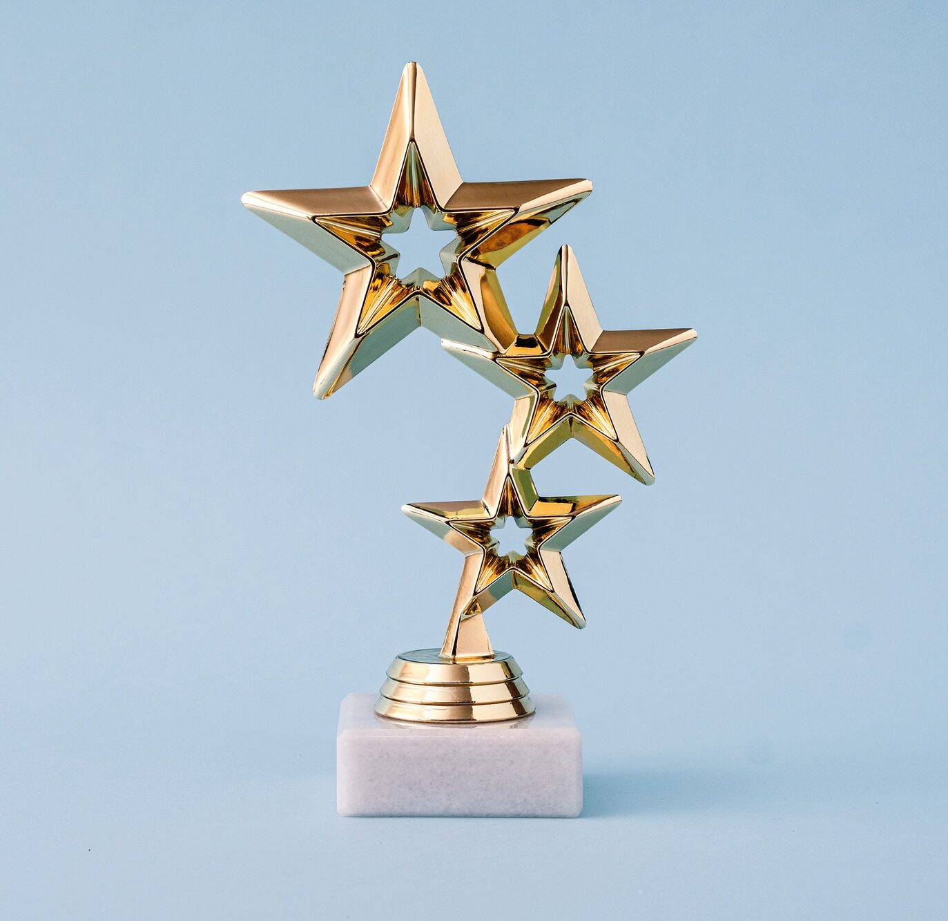 Three star awards for leader and ranking. Golden shiny prize on a pastel blue background.